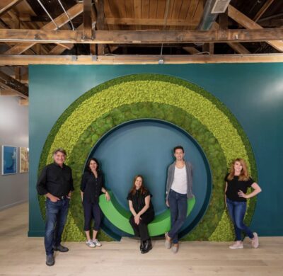 A group of people standing in front of a green wall.