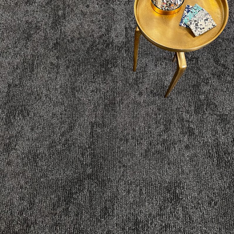 A PARTLY CLOUDY carpet tile with a gold table on it.