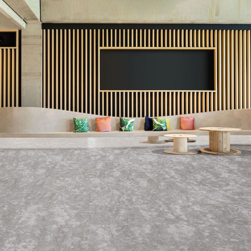 A grey Farafra in a lobby with a wooden floor.