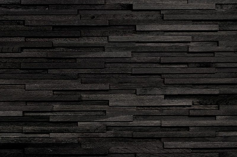 A black brick wall with some wood planks