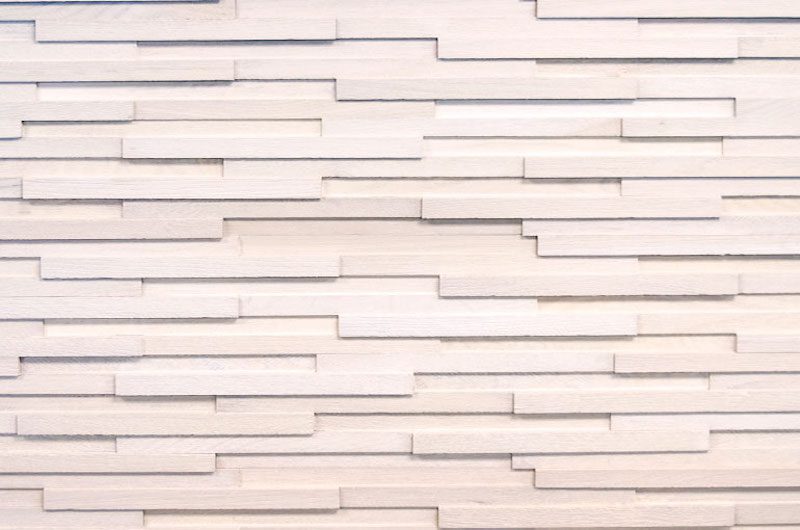 A white wall with many strips of wood.