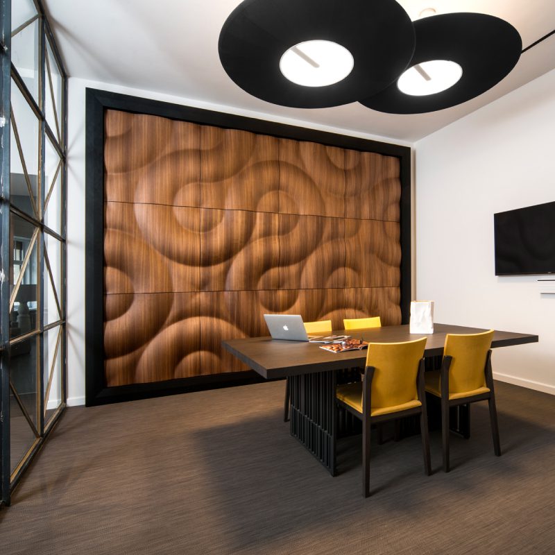 A modern office with a Flintino wooden wall and black chairs.
