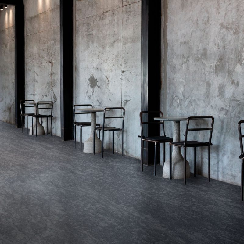 A row of Karakum tables and chairs in a concrete room.
